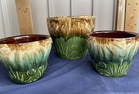 Set of three vintage McCoy glazed ceramic plant pots with Sun Moon and Stars Art Deco design, showing detail and color.