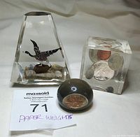 Three vintage paperweights: trapezoidal with Canada Goose figurine, cube with coins, and half-sphere with penny