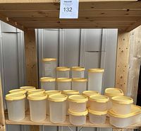 Front view showing multiple vintage Tupperware containers with yellow lids, arranged in rows on wooden shelves.
