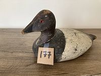 Full side view of the antique duck decoy displaying overall body shape, paint wear, and red eye detail.