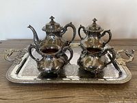 Full tea service set of six pieces arranged on the ornate rectangular serving tray showing handles and embossed details.