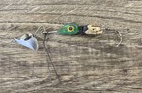 Green lure with yellow eye and metal spinner photographed on wooden background