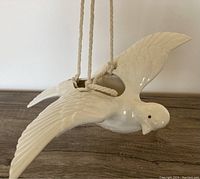 Side view of the ceramic dove bird planter showing detailed wings and face with attached hanging rope.