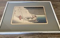 Full view of framed Japanese art print showing snowy landscape with houses and figure in red holding umbrella.