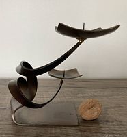 Side angle showing the sculptural curved metal base and two square candle holders with spikes.