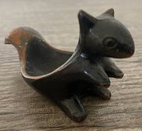 Close-up of a single bronze squirrel sculpture showing worn patina and hollow body