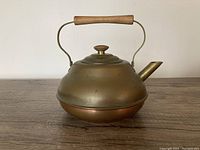 Full view of a vintage copper tea kettle with wooden handle and knob.