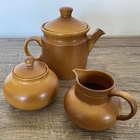 Photo of vintage Myott ceramic tea set showing teapot with lid, sugar bowl with lid, and milk pitcher in brown gradient finish on a wood surface.