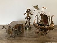 All three copper mechanical music boxes placed side by side on a wooden surface.