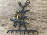 Front view of the Walter Bosse bronze key hanger showing dark bronze color with gold accent highlights on the stylized animal figures and hooks.