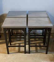Four vintage stools with rectangular grey tops and black metal bases shown from the top and front angles.