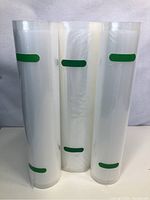 Three new rolls of vacuum sealer bags standing vertically showing their length and green markings.
