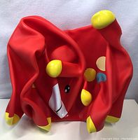 Red inflated animal hopper toy folded flat on surface, showing body, head, and legs with yellow tips and facial features.