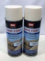 Two SEM Marine Vinyl Coat spray cans with cream caps, labeled off-white color, placed side by side on a grey fabric surface.