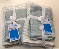 Two bundles each with two dishcloths and one barmop towel in sage green, tied with white elastic bands, labeled with room essentials tags.