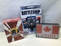 Photo showing three card games: Battleship, Canada, and Opinionator in packaging