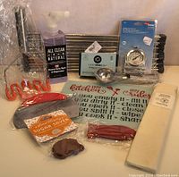 Photo of assorted new kitchenware items including cleaning spray, spatulas, kitchen mat, thermometer, sugar saver, and scrapers.