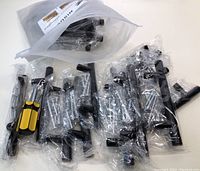 Multiple black metal drawer handles individually wrapped in plastic along with mounting screws, all contained in a large zip lock bag.