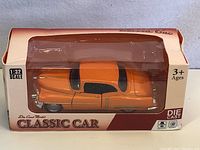 Photo showing the orange die cast classic car in original packaging with 'Classic Car' branding and 1:32 scale label.
