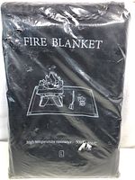 Photo of the fire blanket folded and packaged in plastic. Text on the blanket indicates fire safety purpose and temperature resistance.