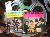 Two Beatles Decca demo singles on 7-inch vinyl in sleeves, shown on a reel.