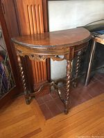 Side front view showing carved apron and turned legs with some wear and damage on lower frame.