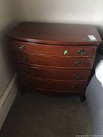 Front view of cherry finish dresser showing four bowed drawers and oval ring pull handles.