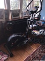 Full side view of HealthRider 830 elliptical cross trainer positioned indoors near windows and radiator with other household items nearby.