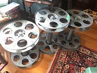 Front view showing all three film reel side tables together on hardwood floor.