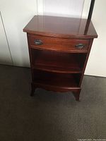 Front view of wooden bedside table showing drawer and shelves.