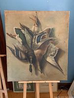 Full view of the oil on canvas painting showing hanging game birds with signs of wear and damage.