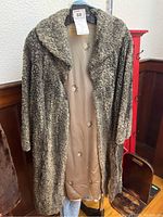 Full frontal view of the vintage Persian lamb fur coat open, showing the outer curly lamb fur and lined interior.