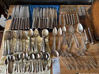Overview of the full cutlery set laid out on a table, showing all knives, forks, and spoons arranged in groups.