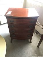 Front view showing four drawers with metal oval handles and curved front design.