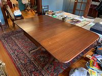 Full view of wooden dining table with drop leaves in an open position showing wood finish and rectangular top shape.