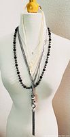 Front view of the layered black and white necklaces displayed on a mannequin
