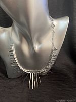 Front view of the silver wavy stick necklace displayed on a mannequin showing geometric arrangement of pendants.