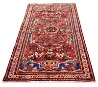 Full front view of rug showing central geometric floral medallion and border pattern on red field