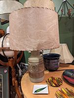 Photo showing a ceramic table lamp with beige and brown geometric pattern base and large brown textured fabric shade.