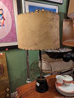 Photo of the atomic style table lamp showing the fabric shade with wear and the geometric metal base on a black stand.