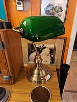 Overall image of the classic banker lamp on a wood surface with a green shade and brass base.
