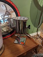 Photo of a chrome spotlight on wooden surface with an adjustable mount and power cord.