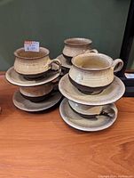 Photo of six stacked Detliv ceramic cups and saucers showing their textured beige and brown glaze and handle design.