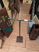 Full view of freestanding industrial toilet paper holder showing base and pipe structure.