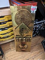 Full view of brass metal wall art piece showing all embossed details and wooden backing