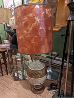 Photo of a retro ceramic table lamp with an orange mottled shade, showing lamp details and texture.