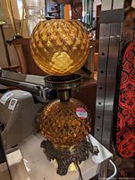 Photo of a vintage amber glass retro table lamp with two textured glass globes and ornate metal base.