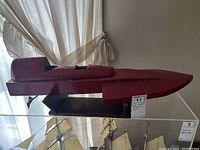 Side view of the classic wooden red speed boat model on a display stand.