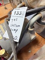 Close-up view of vacuum pump with tag labeled 'Gas Vacuum Pump 945'.