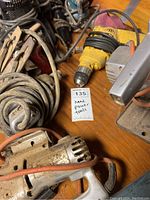 Various used hand power tools including a yellow drill, gray heat gun, and cords showing wear and usage.